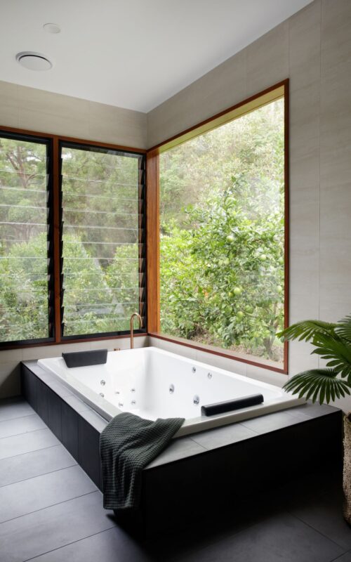 large spa bath in bathroom with cedar timber windows